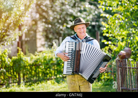 Mann in bayerischer Tracht Akkordeon zu spielen Stockfoto