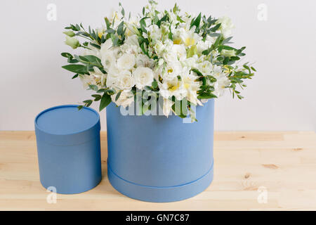 Blumengeschäft, Blumenstrauß in einer runden Box zu arbeiten. duftende Blüten mit weißen Rosen in Hut gegen die verputzte Wand Stockfoto