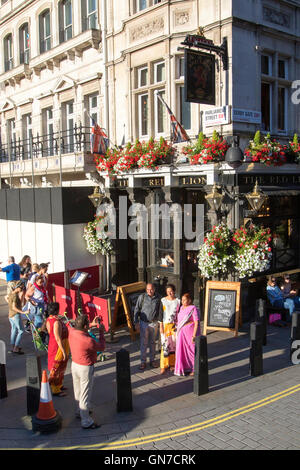 Touristen posieren für ein Foto vor dem Red Lion Pub auf Parliament Street im Zentrum von London Stockfoto