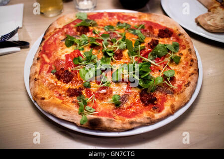 Fleisch fest Pizza mit Peperoni und Hackfleisch, garniert mit Rucola, serviert im restaurant Stockfoto
