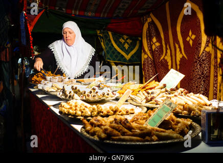 Marokkanerin Verkauf von Süßigkeiten vom Stand auf Straßenmarkt. Stockfoto