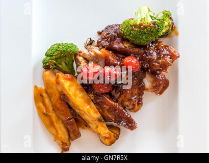 Schweinefleisch Rippe gegrillte und gebratene Kartoffelspalten auf weißen Teller mit Sauce und Gemüse, Gourmet-Küche. Stockfoto