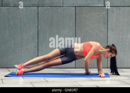 Fit junge Frau tut Sideplanks, ihren Kern zu verstärken, arbeiten auf einer Matte, Lifestyle und Gesundheit-Konzept Stockfoto