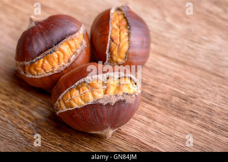 Makro drei geröstete Kastanien auf Holztisch Stockfoto