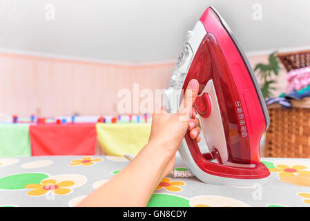 Weibliche Hand greift für das Eisen. Close-up. Stockfoto