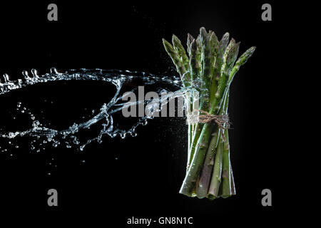 Spargel in Spritzer auf schwarzem Hintergrund. Close-up. Eine Reihe von Obst und Gemüse in Bewegung. Stockfoto