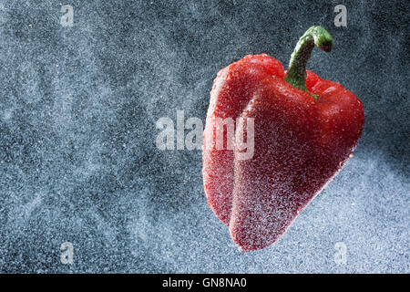 Rote Paprika in einem Spray gegen einen schwarzen Hintergrund. Eine Reihe von Obst und Gemüse in Bewegung. Stockfoto