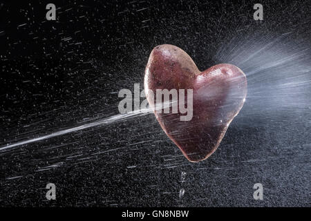 Kartoffeln in Form von Herzen. Auf einem schwarzen Hintergrund. Eine Reihe von Obst und Gemüse in Bewegung. Zum Valentinstag Stockfoto