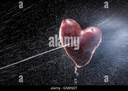 Kartoffeln in Form von Herzen. Auf einem schwarzen Hintergrund. Eine Reihe von Obst und Gemüse in Bewegung. Zum Valentinstag Stockfoto