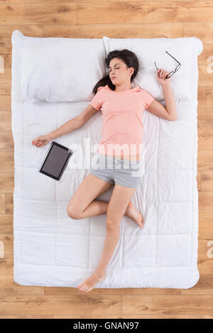Über müde Frau schläft auf Bett Stockfoto