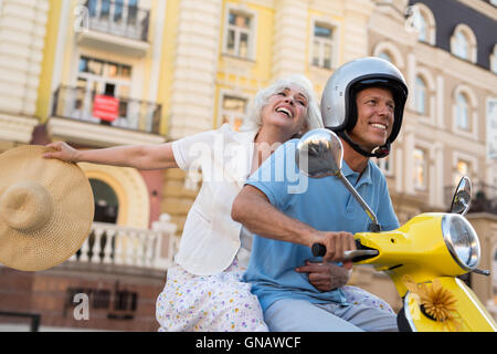 Älteres paar Lächeln fährt Roller. Stockfoto