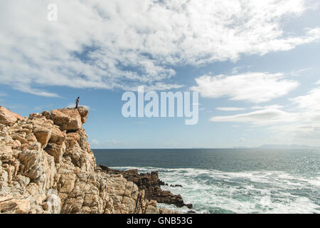 Mädchen stehen auf Felsen über dem Meer an einem bewölkten Tag. Stockfoto