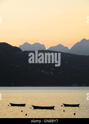 Full-Frame shot der Sonnenuntergang mit leeren Holzboote auf See und Berge Hintergrund Stockfoto