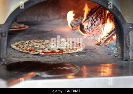 Mann, frisch zubereitete Pizza in einem Holzofen Pizza-Ofen Stockfoto