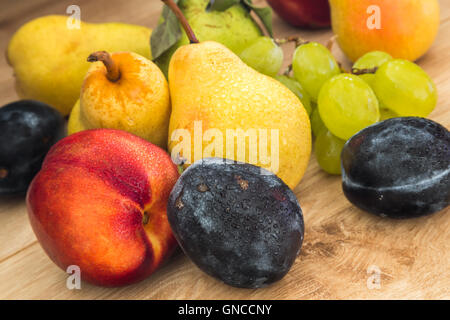 ein paar frische Bio-Birnen, Pflaumen, Weintrauben und Nektarine auf dem Holztisch Stockfoto