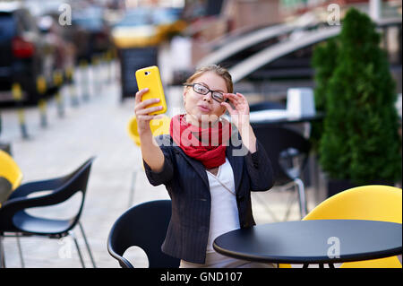 junge Frau in Gläsern macht Selfie im café Stockfoto