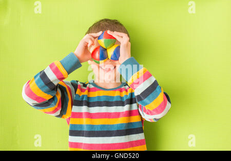 Kleines Mädchen mit fehlenden Zähnen lachen. Bunte Jonglierbälle vor Augen halten. Süße Kindheit Moment. Stockfoto