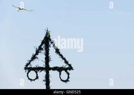 Traditionelle schwedische Mittsommer Pol und blauer Himmel. Maibaum in Silhouette mit Möwe fliegen oben. Stockfoto