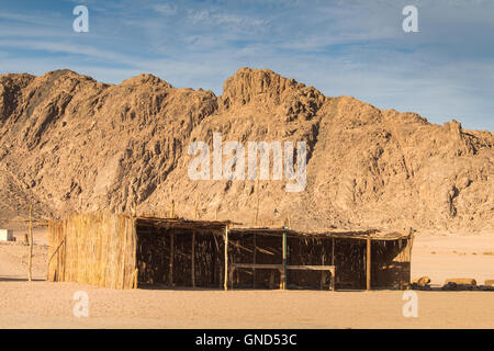 Rocky Mountains in den Sand Farbe in der Wüste in Ägypten. Beduinen, die Gebäude für die Gäste. Bewölkter Himmel. Stockfoto