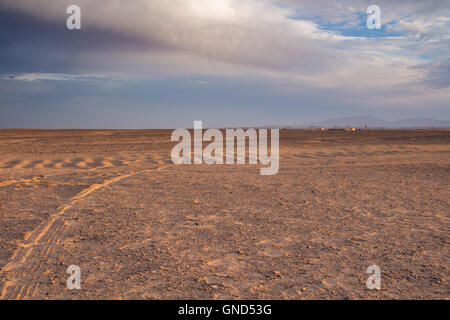 Flache sandige Gelände in der Wüste in Ägypten, in der Nähe der Küste und Stadt Hurghada. Linie der Berge im Hintergrund. Intensive c Stockfoto