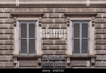 Fassade des Gebäudes eingerichtet nach einem Entwurf des großen Steinblöcken. Zwei Fenster mit grau geschlossen Fensterläden. Rom, Italien. Stockfoto