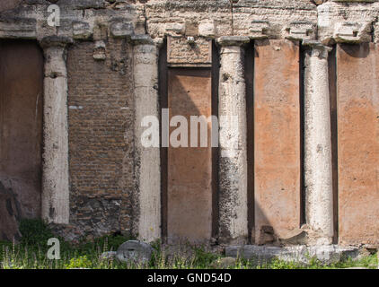 Typische orange Farbe der römischen Architektur, mit vier alten Säulen aus dem ursprünglichen Gebäude. Rom, Italien Stockfoto