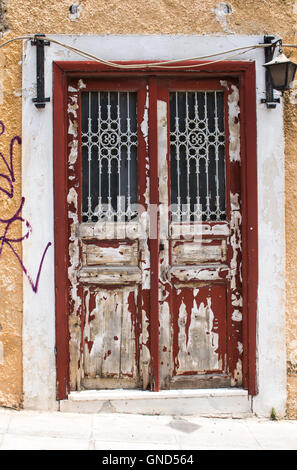 Alte Eingangstür zum Haus mit dunkelroten geschält der Malerei. Weißer Rahmen. Gelbe Fassade. Laterne, die Tür zu erleuchten. Stockfoto