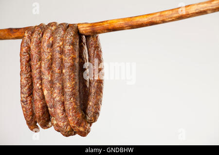 hängende geräucherte Wurst auf einem Stick auf weißem Hintergrund Stockfoto