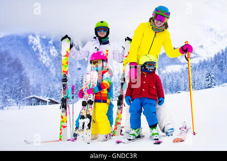 Mutter und Kinder Skifahren in den Bergen. Aktive Mutter und drei Kinder mit Helm, Schutzbrille und Polen. Stockfoto