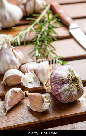 Knoblauch und Rosmarin auf Holztisch. Stockfoto