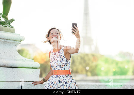 Paris, Frau tut ein Selbstporträt mit Eiffelturm im Hintergrund Stockfoto