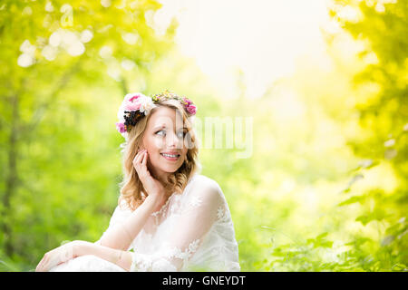 Braut im Brautkleid mit Blumen Kranz, grüner Natur. Stockfoto