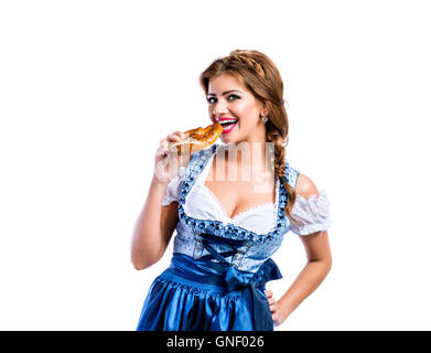 Schöne Frau in bayerischer Tracht hält eine Brezel Stockfoto