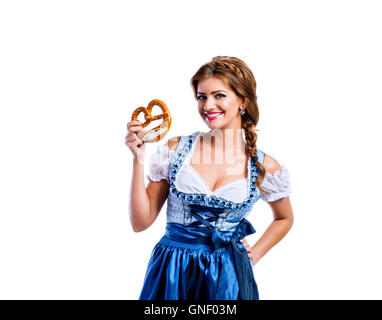 Schöne Frau in bayerischer Tracht hält eine Brezel Stockfoto