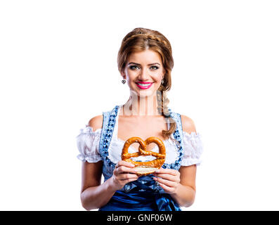 Schöne Frau in bayerischer Tracht hält eine Brezel Stockfoto