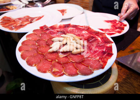 Kellner bereitet spanische ausgehärteten Iberico Schinken und Lende Scheiben auf Teller mit Brot-sticks über Stück Käse Stockfoto