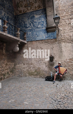 A Street Performer spielt Akkordeon und singt im Stadttor von Obidos, Portugal. Stockfoto