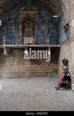 A Street Performer spielt Akkordeon und singt im Stadttor von Obidos, Portugal. Stockfoto