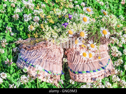 Stroh geflochtenen Hausschuhe sonnigen Sommer Gras und mit Bouquet von Wiesenblumen Stockfoto