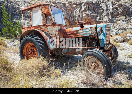 Alter verlassene verrosteter Traktor steht auf dem trockenen Sommer Rasen, Seitenansicht Stockfoto