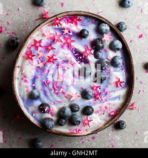 Smoothie-Schüssel mit Heidelbeeren und rosa Blüten Stockfoto