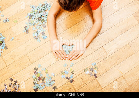 kleines Kind mit Rätseln auf Holzboden zusammen mit Eltern, Lifestyle-Menschen-Konzept, liebevollen Händen miteinander spielen Stockfoto