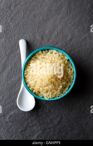 Essen Hintergrund, Reis Nahaufnahme in ethnischen Schüssel auf dunkle Oberfläche, Draufsicht, vertikale Zusammensetzung Stockfoto