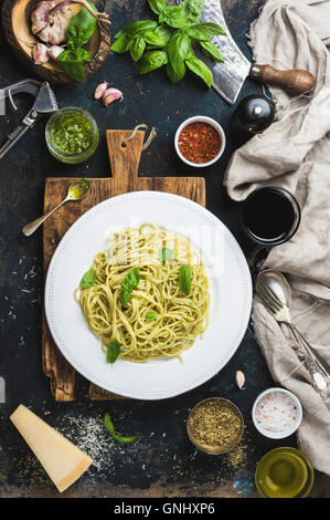 Italienische Pasta-Essen. Spaghetti mit Pesto-Sauce und frischem Basilikum, Parmesan-Käse und Gewürzen serviert mit Glas Wein auf rustikal Stockfoto