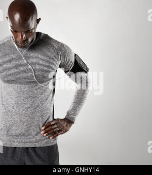 Afrikanische Männermodel tragen Kopfhörer Musik vor grauem Hintergrund zu hören. Fit junge Mann, der mit seinen Händen auf den Hüften und Stockfoto