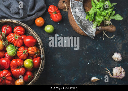 Frische bunte Reifen Herbst Urtomaten in Korb, grüner Basilikum, Knoblauch und Kräuter chopper Messer für gesundes Kochen oder m Stockfoto