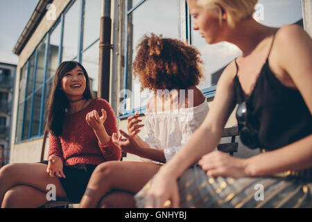 Multiethnische Gruppe von Freundinnen im Freien sitzen und reden. Junge Frauen sitzen auf Balkon. Stockfoto