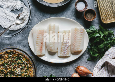 Vier Kabeljaufilet und dem Rest der Zutaten für Ofen gebratene Fischfilets werden von oben fotografiert. Stockfoto
