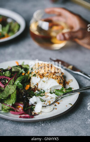 Ein halb gegessen gebratene Fisch zusammen mit etwas Salat wird von der Seite fotografiert. Stockfoto