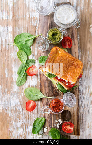 Low-Carb glutenfrei Cloud Brot vegetarischen Sandwich mit Spinat, Avocado, Feta Käse, Tomaten und Pesto-Sauce, serviert auf Messers Schneide Stockfoto